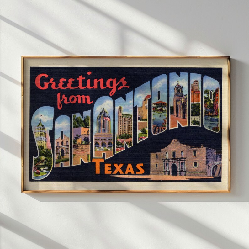 May include: Framed vintage postcard print with the text "Greetings from San Antonio Texas." The postcard features a collage of San Antonio landmarks and buildings, with a dark blue background and a gold frame.