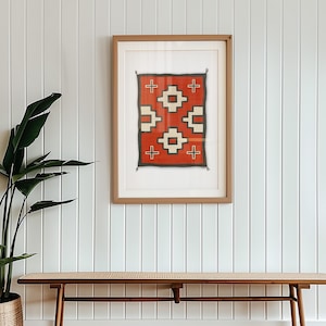 May include: A framed print of a red, white, and black geometric pattern rug. The rug is in a wooden frame and is hanging on a white wall.