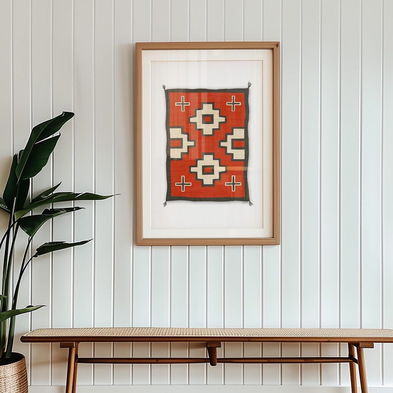 May include: A framed print of a red, white, and black geometric pattern rug. The rug is in a wooden frame and is hanging on a white wall.