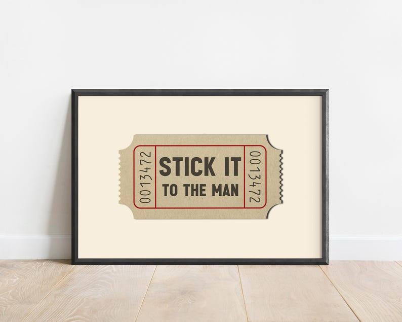 May include: A framed print of a vintage ticket with the text "STICK IT TO THE MAN" printed on it. The ticket has the numbers 0013472 printed on the right side and 0013472 printed on the left side.