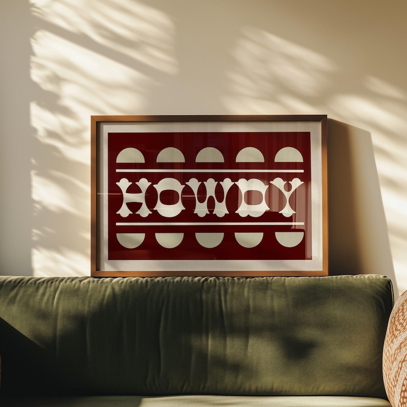 May include: A framed print with a red background and white geometric design. The design features a repeating pattern of semi-circles and the word "HOWDY" in a stylized font.