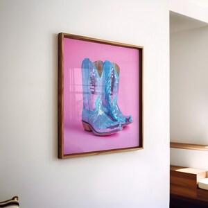 May include: A framed photograph of a pair of blue sequined cowboy boots on a pink background.