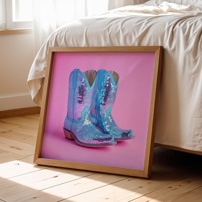May include: A pair of blue cowboy boots with a mirrored finish, set against a pink background.