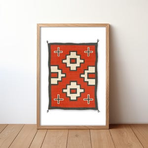 May include: A framed print of a Native American rug with a geometric pattern in red, white, and black. The rug is framed in a natural wood frame.