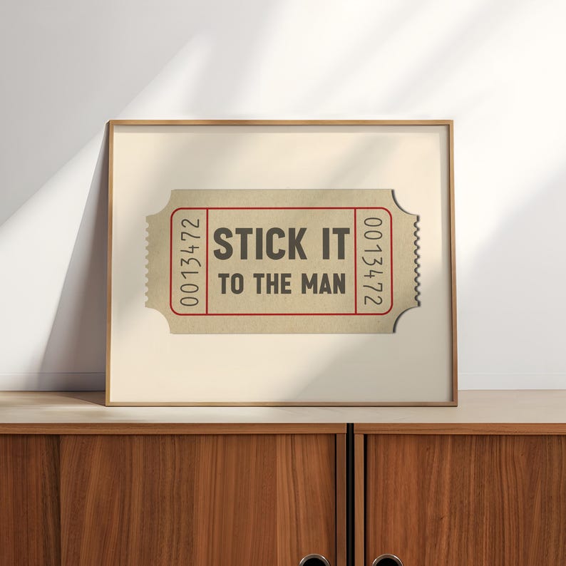 May include: A framed print of a vintage ticket with the text "STICK IT TO THE MAN" and the number "0013472" on each side.