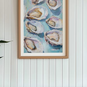 May include: A framed painting of a cluster of oysters on a light blue background. The oysters are painted in a realistic style with shades of white, pink, and yellow.