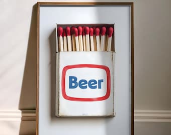 May include: A framed print of a matchbox with red match heads and the word "Beer" in blue letters on a white background.