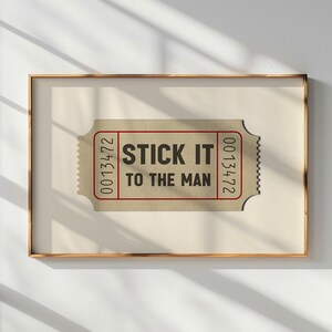 May include: A brown ticket with the text "STICK IT TO THE MAN" and the numbers "0013472" on the right side and "0013472" on the left side.