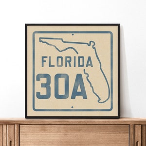 May include: A framed print of a vintage-style sign with a blue outline of the state of Florida and the text "FLORIDA 30A" in blue.
