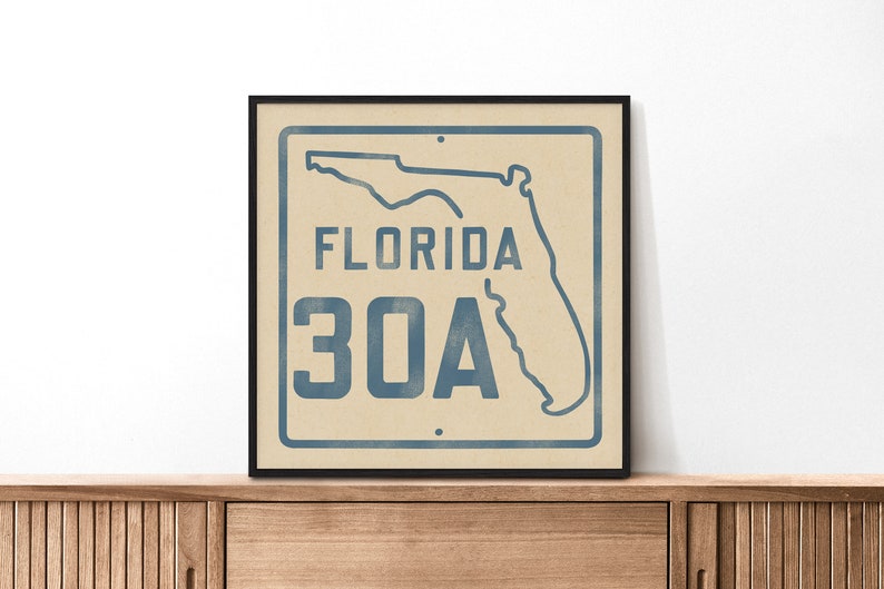 May include: A framed print of a vintage-style sign with a blue outline of the state of Florida and the text "FLORIDA 30A" in blue.