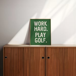 May include: A green framed poster with white text that reads "WORK HARD. PLAY GOLF."