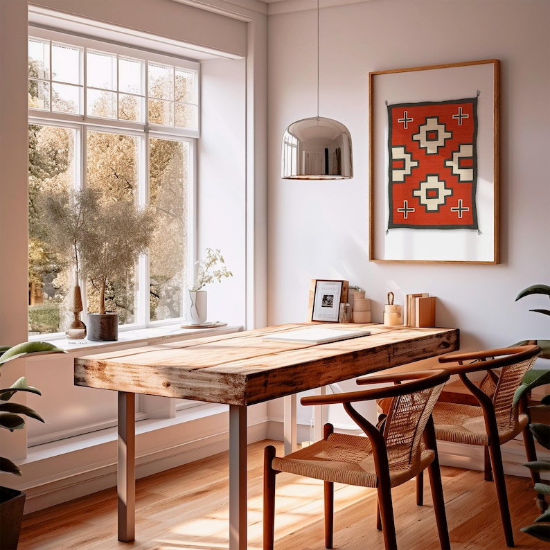 May include: A wooden desk with a rustic finish, two woven chairs, and a silver pendant light. A framed red, white, and black geometric print hangs on the wall above the desk.