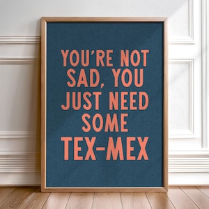 以下が含まれることがあります： 青い背景に白い文字で「You're not sad, you just need some Tex-Mex」と書かれた額装されたプリント。文字は明るいオレンジ色です。