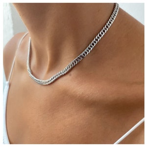 Peut inclure: Un collier en chaîne de curb argenté. La chaîne est épaisse et a un design de maillon épais et carré.