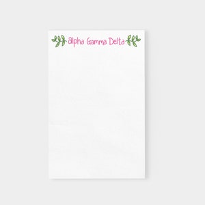 May include: White notepad with a pink "Alpha Gamma Delta" title and green leafy vines on either side.