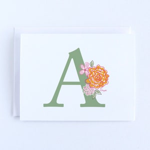 May include: A green letter A with a floral design. The flowers are orange, pink, and green.
