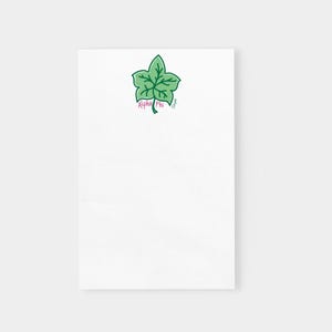 May include: White notepad with a green ivy leaf illustration at the top. The leaf has dark green outlines and lighter green fill. The text "Alpha Phi" is in pink below the leaf.