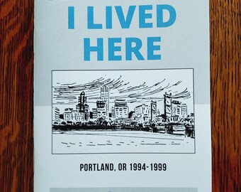 May include: A zine titled I LIVED HERE with the subtitle PORTLAND, OR 1994-1999 by Sierra Tierra issue #1. The cover features a black and white ink sketch of a city skyline above a body of water, with the date JAN 2026 printed in the top left corner.