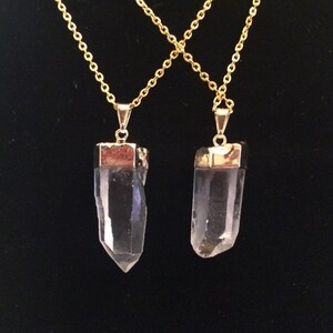 Puede incluir: Dos collares de cadena dorada con colgantes de punta de cristal de cuarzo transparente. Los colgantes est&aacute;n engastados en metal dorado.