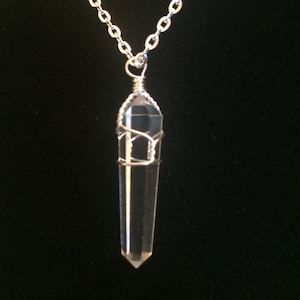 May include: A silver chain necklace with a clear quartz crystal pendant wrapped in silver wire.