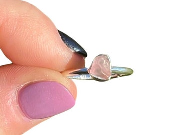 May include: A silver ring with a pink heart-shaped rose quartz stone.
