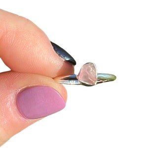 May include: A silver ring with a pink heart-shaped rose quartz stone.