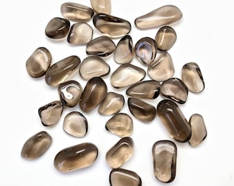 May include: A collection of smoky quartz tumbled stones. The stones are various shades of brown and gray, and they are all smooth and polished.