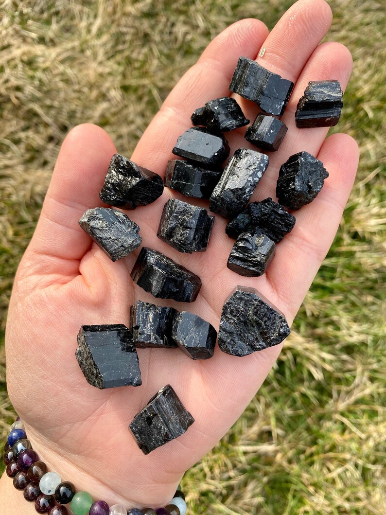 May include: A collection of black tourmaline crystals, also known as schorl, in various sizes and shapes. The crystals are raw and have a natural, rough texture.
