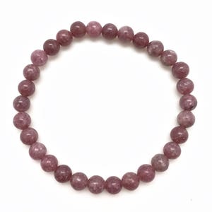 Puede incluir: Un brazalete de piedras preciosas rosa y blancas con cuentas redondas.