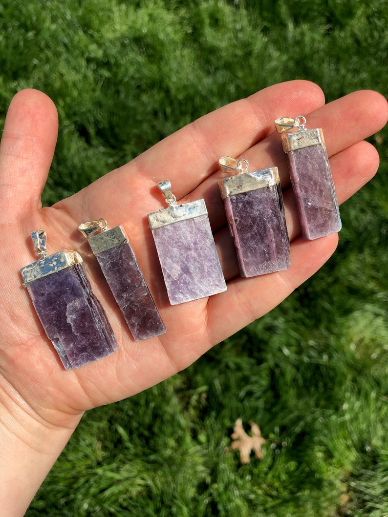 May include: Six silver pendant charms with purple lepidolite crystal stones. The stones are rectangular and have a natural, raw look. The pendants are ready to be added to a necklace or bracelet.
