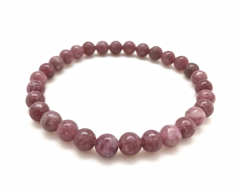 Puede incluir: Un brazalete de piedra de lepidolita rosa con cuentas redondas.