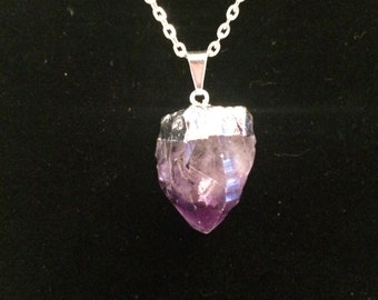 Könnte beinhalten: Eine silberne Kettenkette mit einem Anhänger aus violettem Amethystkristall. Der Kristall ist eine rohe, natürliche Spitze mit einer silberfarbenen Kappe.