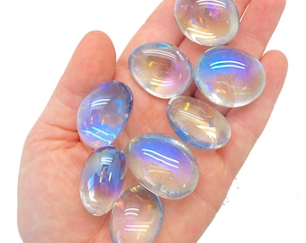 May include: A collection of eight iridescent clear quartz tumbled stones. The stones are smooth and polished, with a rainbow sheen.