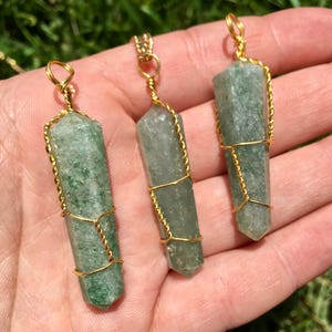 Puede incluir: Tres colgantes de cristal hexagonal, de color verde claro y semitransl&uacute;cido, cada uno envuelto en un alambre fino y retorcido de color dorado. Los cristales tienen una terminaci&oacute;n puntiaguda en la base y un peque&ntilde;o lazo de alambre arriba.