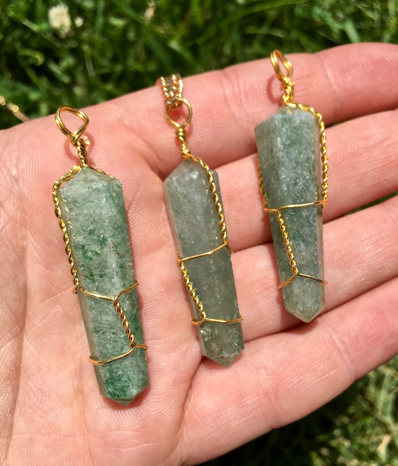 Puede incluir: Tres colgantes de cristal hexagonal, de color verde claro y semitransl&uacute;cido, cada uno envuelto en un alambre fino y retorcido de color dorado. Los cristales tienen una terminaci&oacute;n puntiaguda en la base y un peque&ntilde;o lazo de alambre arriba.