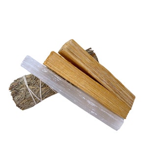 Pu&ograve; includere: Un set di tre bastoncini per la purificazione, tra cui un mazzo di salvia, un bastoncino di palo santo e una bacchetta di selenite. I bastoncini sono disposti a forma di triangolo su uno sfondo bianco.