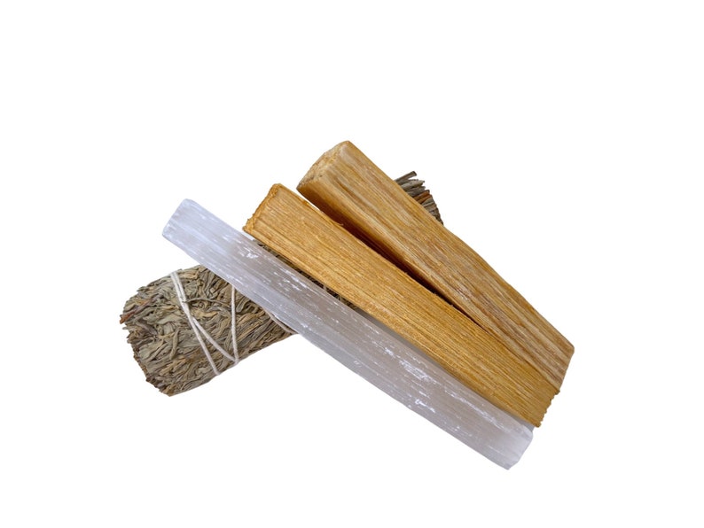 Pu&ograve; includere: Un set di tre bastoncini per la purificazione, tra cui un mazzo di salvia, un bastoncino di palo santo e una bacchetta di selenite. I bastoncini sono disposti a forma di triangolo su uno sfondo bianco.