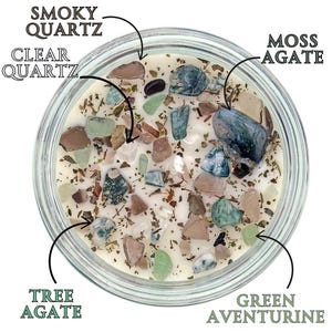 May include: A clear glass jar filled with a white candle and various types of crystals, including clear quartz, smoky quartz, moss agate, tree agate, and green aventurine.