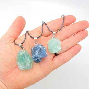 Puede incluir: Tres collares de cristal en bruto en cordones negros. Los cristales son verde claro, verde oscuro y azul gris&aacute;ceo.