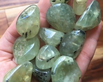 May include: A collection of green aventurine tumbled stones with black inclusions. The stones are smooth and polished, and they have a variety of shapes and sizes.