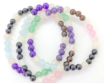 Può includere: Set di sei braccialetti con perline di vari colori, tra cui viola, verde, rosa, bianco e nero.