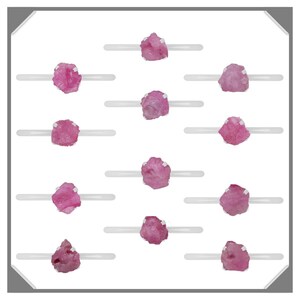 May include: Twelve pink rough gemstones displayed on white stands. The gemstones are various sizes and shapes.
