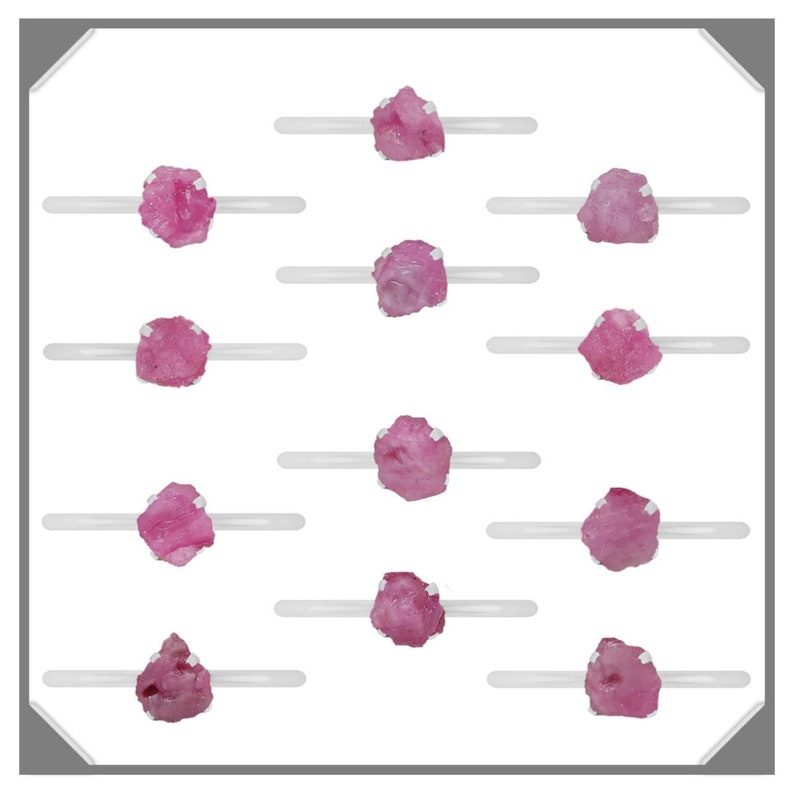 May include: Twelve pink rough gemstones displayed on white stands. The gemstones are various sizes and shapes.