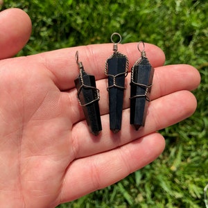 Pode incluir: Tr&ecirc;s pingentes de cristal de obsidiana preta envoltos em fio de prata. Cada pingente tem um la&ccedil;o na parte superior para prender a um colar ou pulseira.