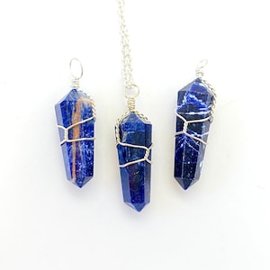 May include: Three wire-wrapped blue sodalite crystal pendants. The crystals are all different shapes and sizes, and they are all wrapped in silver wire. The pendants are hanging from a white background.