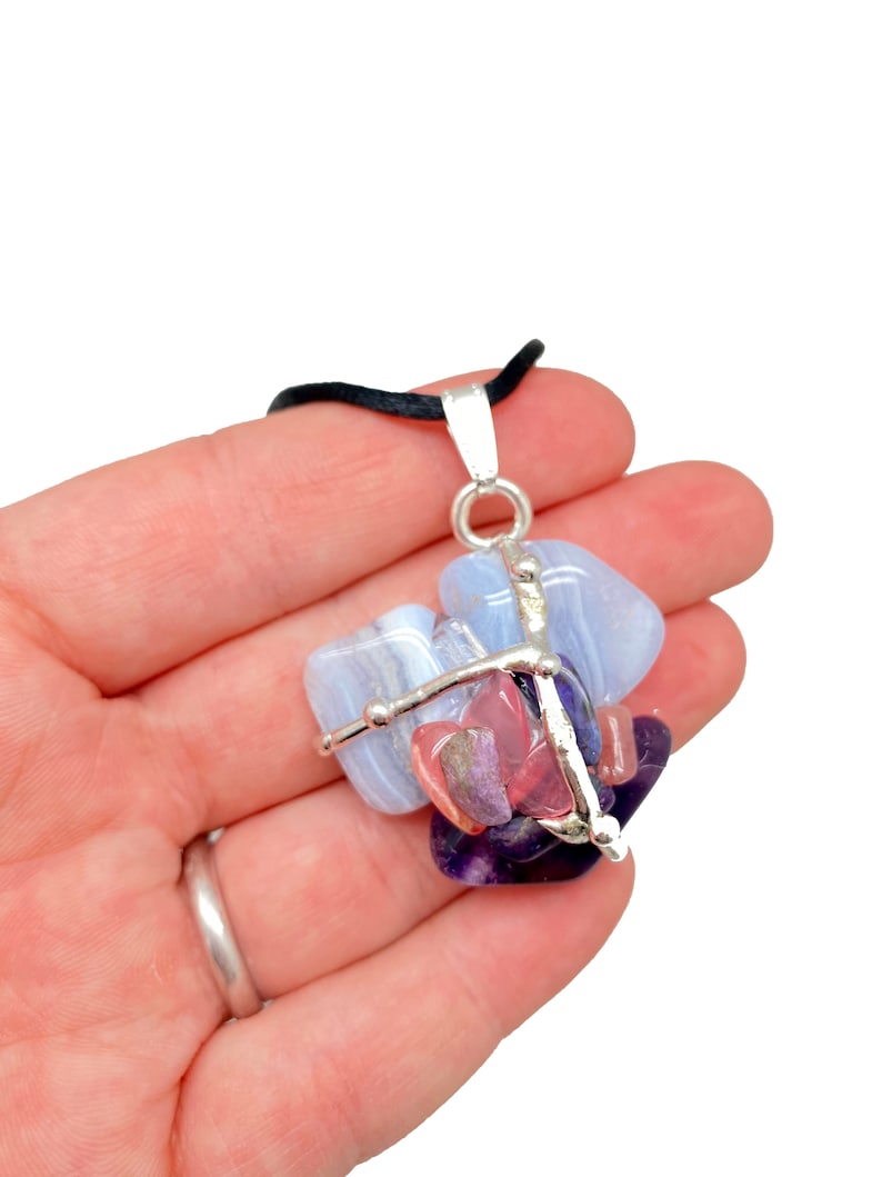 May include: A silver wire wrapped pendant with blue, pink, and purple gemstones. The pendant is on a black cord.