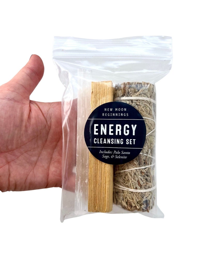 Pu&ograve; includere: Un sacchetto di plastica trasparente contenente un set di strumenti per la pulizia energetica. Il set include un bastoncino di selenite bianco, un bastoncino di palo santo marrone e un mazzo di salvia bianca. Il sacchetto ha un'etichetta che recita "New Moon Beginnings Energy Cleansing Set Includes: Palo Santo Sage & Selenite"