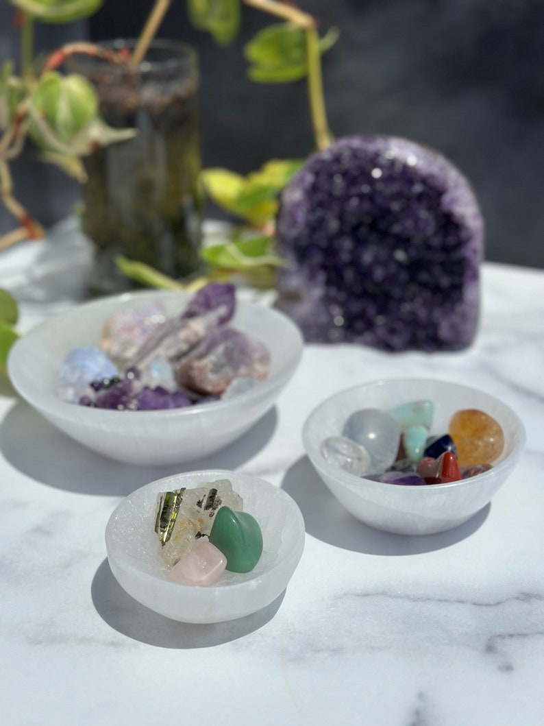 Pu&ograve; includere: Tre ciotole di selenite bianca riempite di cristalli colorati. Le ciotole sono su una superficie di marmo bianco. La ciotola pi&ugrave; grande contiene cristalli di ametista, quarzo rosa e quarzo trasparente. La ciotola media contiene una variet&agrave; di cristalli, tra cui ametista, quarzo trasparente e citrino. La ciotola pi&ugrave; piccola contiene un cristallo di aventurina verde, un cristallo di quarzo rosa e un cristallo di quarzo trasparente.