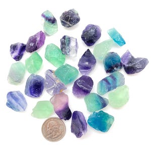 Puede incluir: Una colecci&oacute;n de cristales de fluorita en varios tonos de verde, azul y morado. Los cristales son &aacute;speros y tienen un aspecto natural sin pulir.