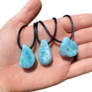 May include: Three blue and white gemstone pendants on black cords. The pendants are teardrop shaped and have a marbled appearance.
